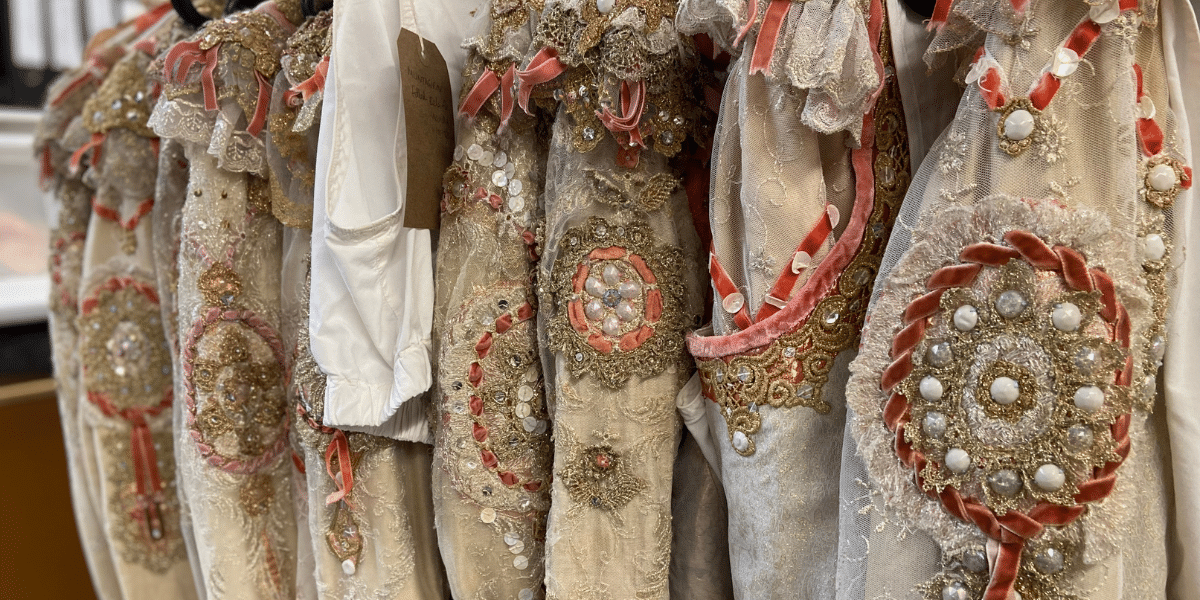 A row of ornate, bejewelled costumes with intricate detailing and ribbons.