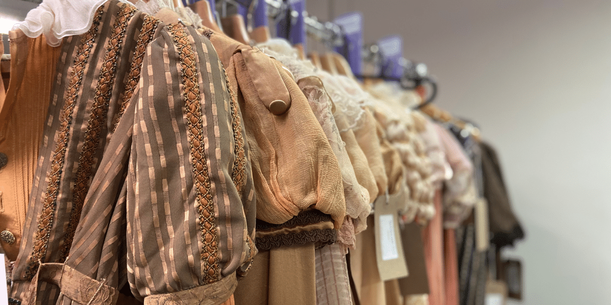 Assorted costumes on racks in a store with a focus on brown and beige tones.